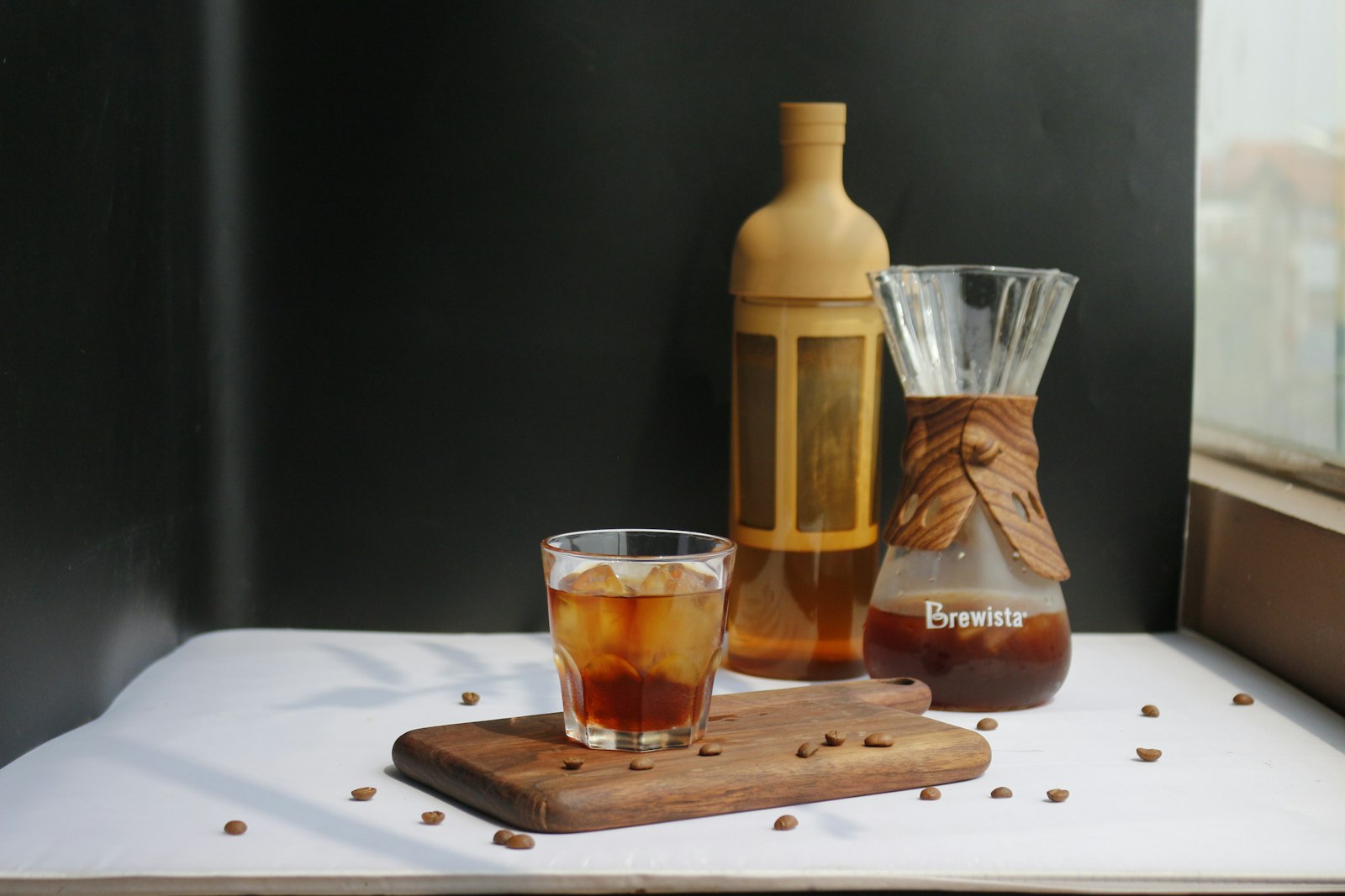 Chai và bình cold brew cà phê cùng ly trên khay gỗ